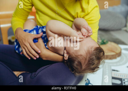 Stanco Baby girl strofinarsi gli occhi sul giro di madre Foto Stock