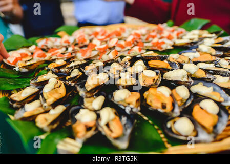 Vassoio di cozze cotte con spezie servito ad una festa gastronomica. Foto Stock