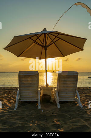 Sunrise in Nusa Dua beach, una coppia di bianco sdraio ed un ombrellone / ombrello per godere della bellissima alba, bella Bali Foto Stock
