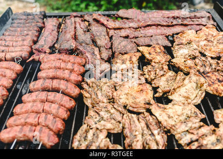 Salsicce, carne di maiale e di pollo arrostito su un barbecue, visto da sopra. Foto Stock