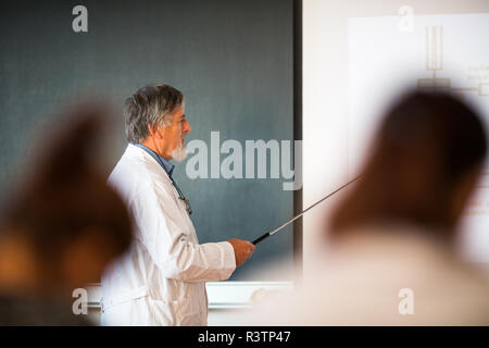 Senior professore di chimica dando una lezione di fronte classroom Foto Stock