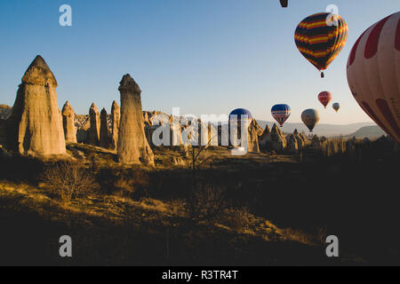 Goreme, Turchia - Aprile 4, 2012: i palloni ad aria calda per i turisti volare sopra le formazioni rocciose a sunrise nella valle della Cappadocia. Foto Stock
