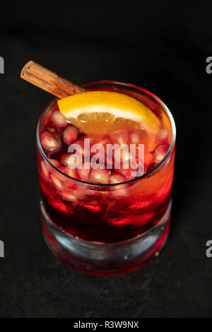 Cocktail di rosso con melograno, limone e alcool isolato con sfondo nero Foto Stock