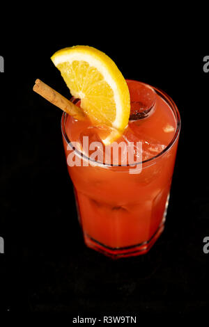 Cocktail di rosso con succhi di frutta rossa, alcol e uno spicchio di lime con isolati su sfondo nero Foto Stock