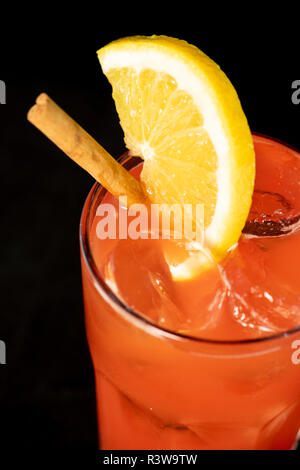 Cocktail di rosso con succhi di frutta rossa, alcol e uno spicchio di lime con isolati su sfondo nero Foto Stock