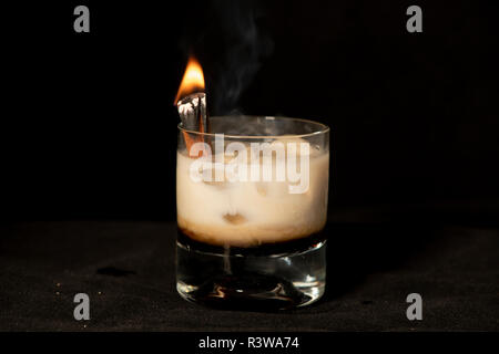 Flaming cannella cocktail con kahlua, baileys Irish cream e sambuca isolato con sfondo nero Foto Stock