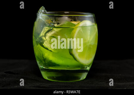 Cocktail di verde con gin, bitter limone, basilico e limone con isolati su sfondo nero Foto Stock