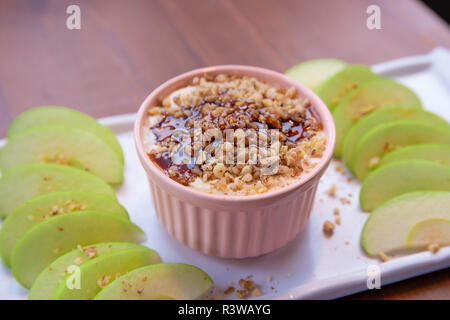 Caramel Apple Dip con dadi, caramello medicazione e freschi fette di mela su legno Foto Stock