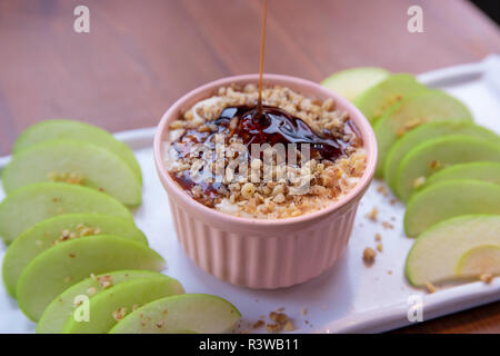 Caramel Apple Dip con dadi, caramello medicazione e freschi fette di mela su legno Foto Stock