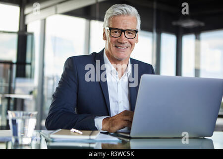 Imprenditore lavora in ufficio, con il computer portatile Foto Stock