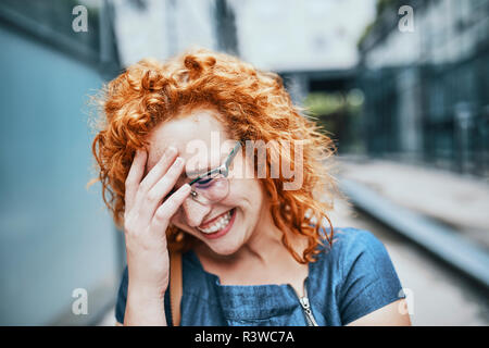 Ritratto di una giovane donna redheaded indossando occhiali, sorridente Foto Stock