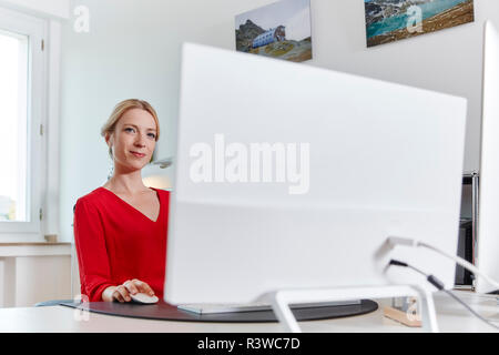 Ritratto di giovane donna che lavorano su computer presso la scrivania in ufficio Foto Stock