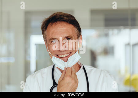 Ritratto di un medico, rimozione mascherina chirurgica, sorridente Foto Stock