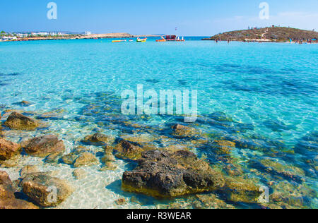 Immagine di Nissi mozzafiato spiaggia di Agia Napa, Cipro. La sabbia bianca e mare fondo sotto il turchese trasparente azzurro acqua in una baia. Cloudles caldo Foto Stock