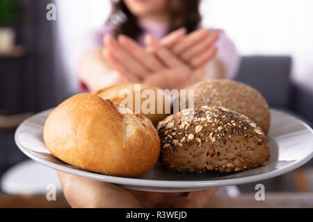 Close-up di una donna di mano rifiutando il pane offerto da persona Foto Stock