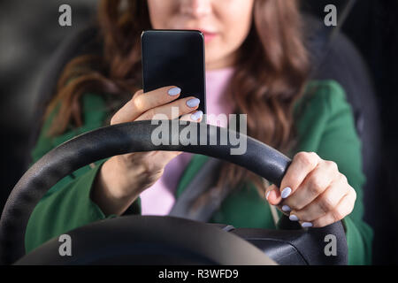 Close-up di una donna di mano gli spostamenti in auto utilizzando lo smartphone Foto Stock