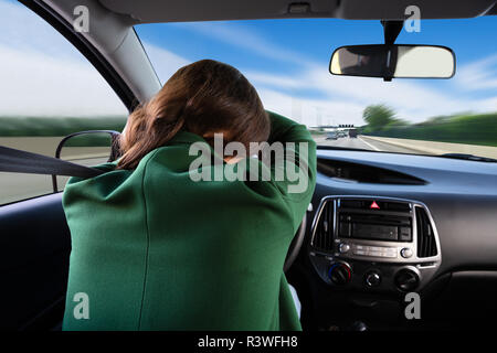 Vista posteriore di una giovane donna che dorme durante un viaggio in auto Foto Stock