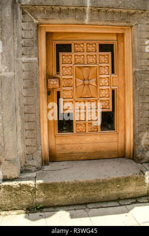 Dilijan, Armenia, 24 agosto 2018: vetrata scolpita con croce di legno,bassa porta di ingresso,PER L inchino del capo nelle chiese del monastero di Hagharts Foto Stock