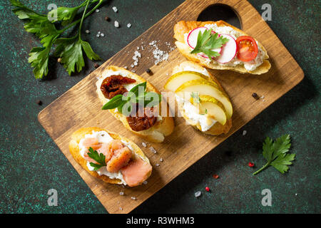 Antipasti italiani spuntini impostato per il vino. Varietà Spaghetti con formaggio a pasta morbida, pera, Rafano, salmone e pomodori secchi serviti su un rustico in legno su scheda Foto Stock