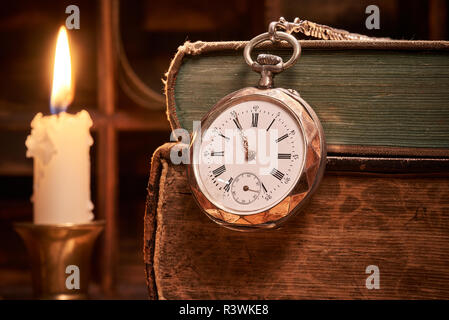 Libri antichi con antico orologio da tasca a lume di candela Foto Stock