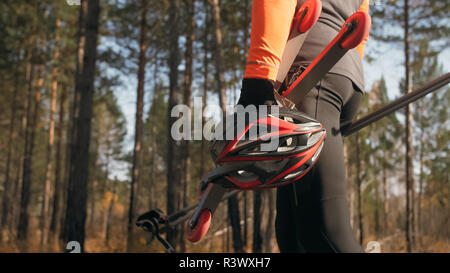 La formazione di un atleta sul rullo pattinatori. Il biathlon ride sul rullo di sci con bastoncini da sci, nel casco. Allenamento di autunno. Sport a rullo. Uomo adulto rid Foto Stock