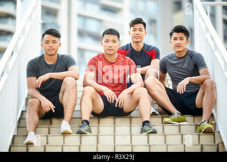 Outdoor ritratto di un team di quattro giovani asiatici atleti seduti sui gradini Foto Stock