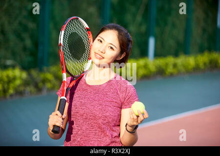 Outdoor ritratto di una giovane asian giocatore di tennis guardando sorridente della fotocamera Foto Stock