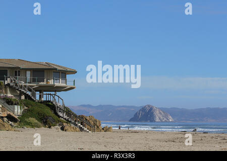 Una casa sulla spiaggia che si affaccia su Morro Rock, San Luis Obispo County, California, Stati Uniti d'America. (Solo uso editoriale) Foto Stock