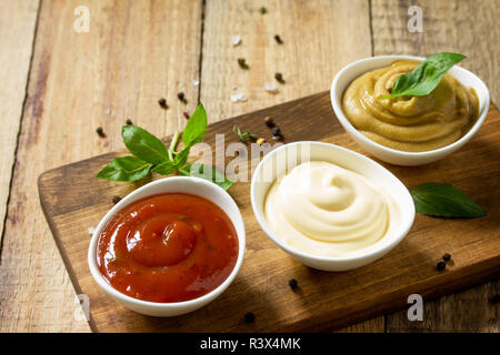 Set di salse - ketchup, maionese e mostarda su un tavolo di legno. Copia dello spazio. Foto Stock