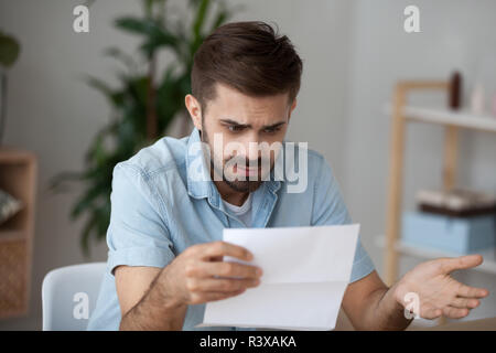 Confuso maschio di lettura la lettera sconvolta dalla notizia Foto Stock