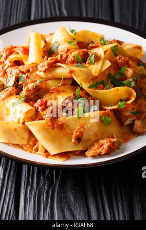 Taccozzette con Stracotto (pasta con carne di maiale brasato ragu) close-up su una piastra sulla tavola nera verticale. Foto Stock