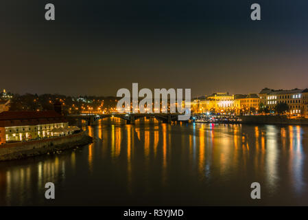Illuminata edifici classici e le luci di strada riflettendo sul fiume Moldava a Praga in una fredda notte invernale - 1 Foto Stock