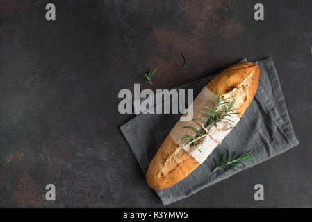 Freschi Fatti in casa il pane artigianale con rosmarino su sfondo rustico, vista dall'alto, copia dello spazio. Pasta madre mini baguette di pane. Foto Stock