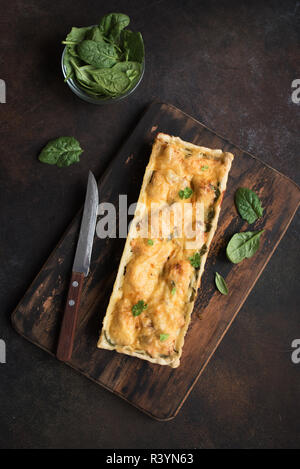 Salmone Torta di Spinaci (quiche) con formaggio rustico scuro dello sfondo. Fatti in casa crostata di salmone per un sano pranzo, vista dall'alto, copia dello spazio. Foto Stock