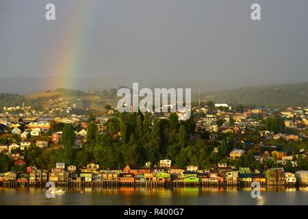 Rainbow sopra la città di palafitte, chiamato palafitos, nella luce del mattino, Castro, isola di Chiloé, Cile Foto Stock