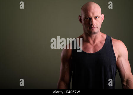 Bald muscolare di uomo che indossa tank top contro sfondo colorato Foto Stock