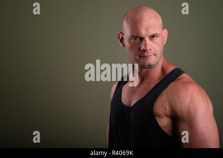 Bald muscolare di uomo che indossa tank top contro sfondo colorato Foto Stock