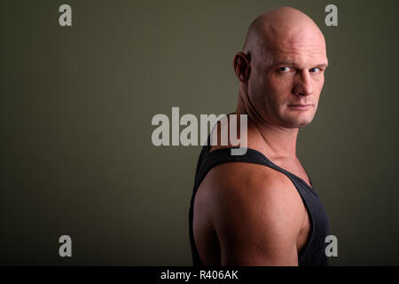 Bald muscolare di uomo che indossa tank top contro sfondo colorato Foto Stock