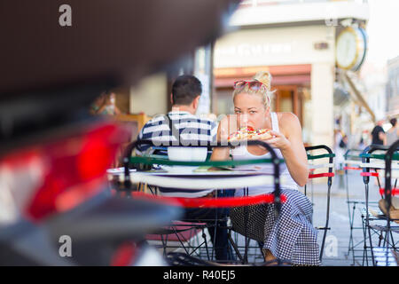 Donna di mangiare pizza outdoor in caffetteria. Foto Stock