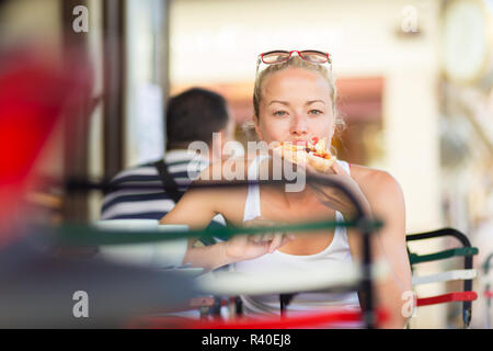 Donna di mangiare pizza outdoor in caffetteria. Foto Stock