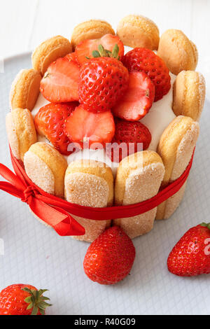 Malakoff Charlotte, dessert francese con fragole, legato con nastro di scarlatto, tazza di caffè, ciotola con fragole su tavola bianca. Dessert senza forno. Foto Stock