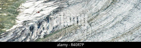 Panorama di rosso MD elicottero volando sopra la massa di ghiaccio del ghiacciaio di Aletsch. Il ghiacciaio di Aletsch (tedesco: Aletschgletscher) o il grande ghiacciaio di Aletsch Foto Stock