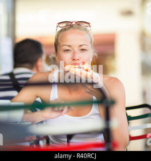 Donna di mangiare pizza outdoor in caffetteria. Foto Stock