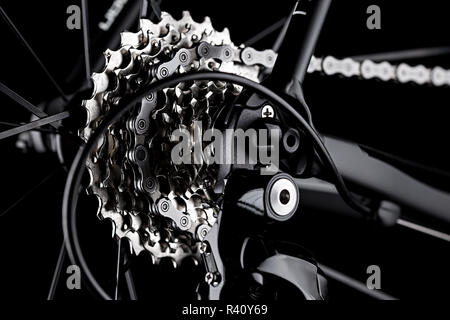 Noleggio bici deragliatore posteriore ingranaggio catena casette dettaglio chiudere up shot nero lo sfondo scuro Foto Stock