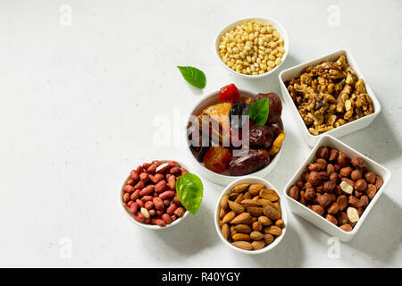 Vari dadi in una ciotola di ceramica e Frutta Secca su una pietra chiara tabella. Il concetto di una sana Dessert. Copia dello spazio. Foto Stock