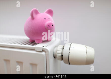 Rosa salvadanaio sul radiatore. Concetto di risparmio energetico. Foto Stock