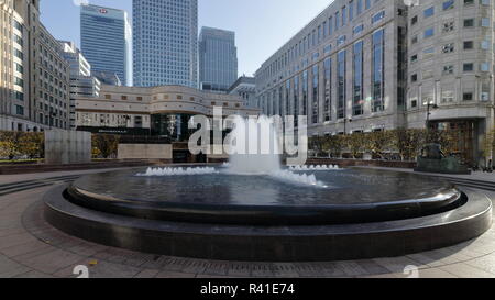 Cabot Square fontana a Canary Wharf a Londra. La domenica mattina presto. Ultimi giorni caldi dell'autunno nel 2018. In pochi minuti la gente si avvia andare al carrello Foto Stock