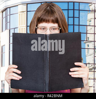 Ragazza legge big book e apartment house Foto Stock