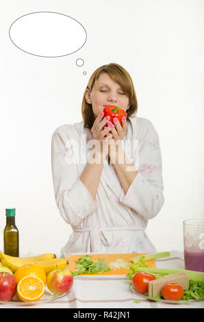 Ragazza giovane odorare un vegetariano peperoni con la nuvola di pensiero sopra la sua testa Foto Stock