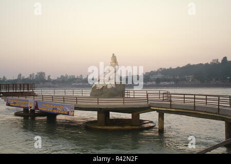 Dio indù Shiva statua a Rishikesh, India. Fiume ganga scorre in background Foto Stock